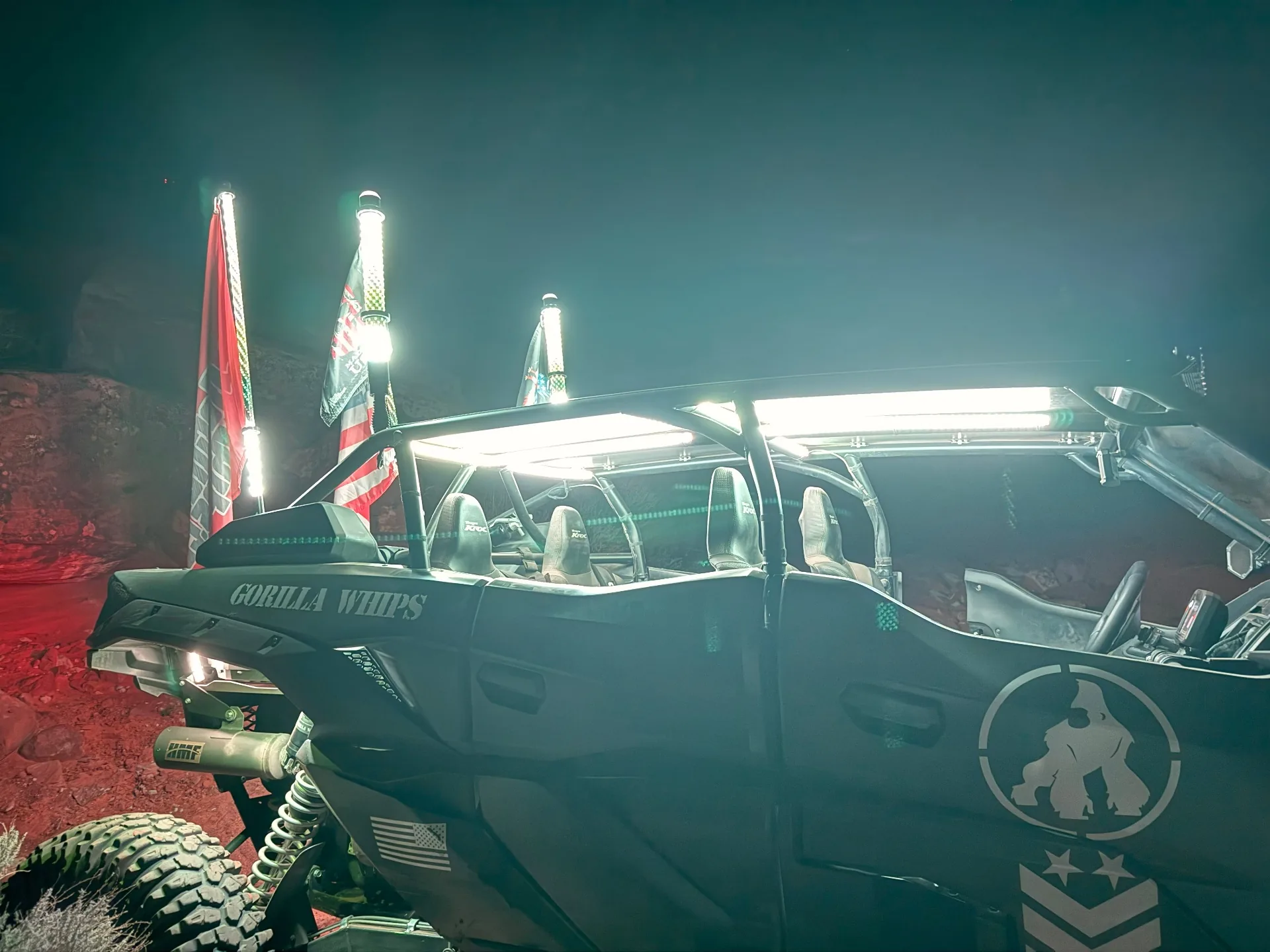 Off-road vehicle with illuminated whips and flags on a red-rock trail