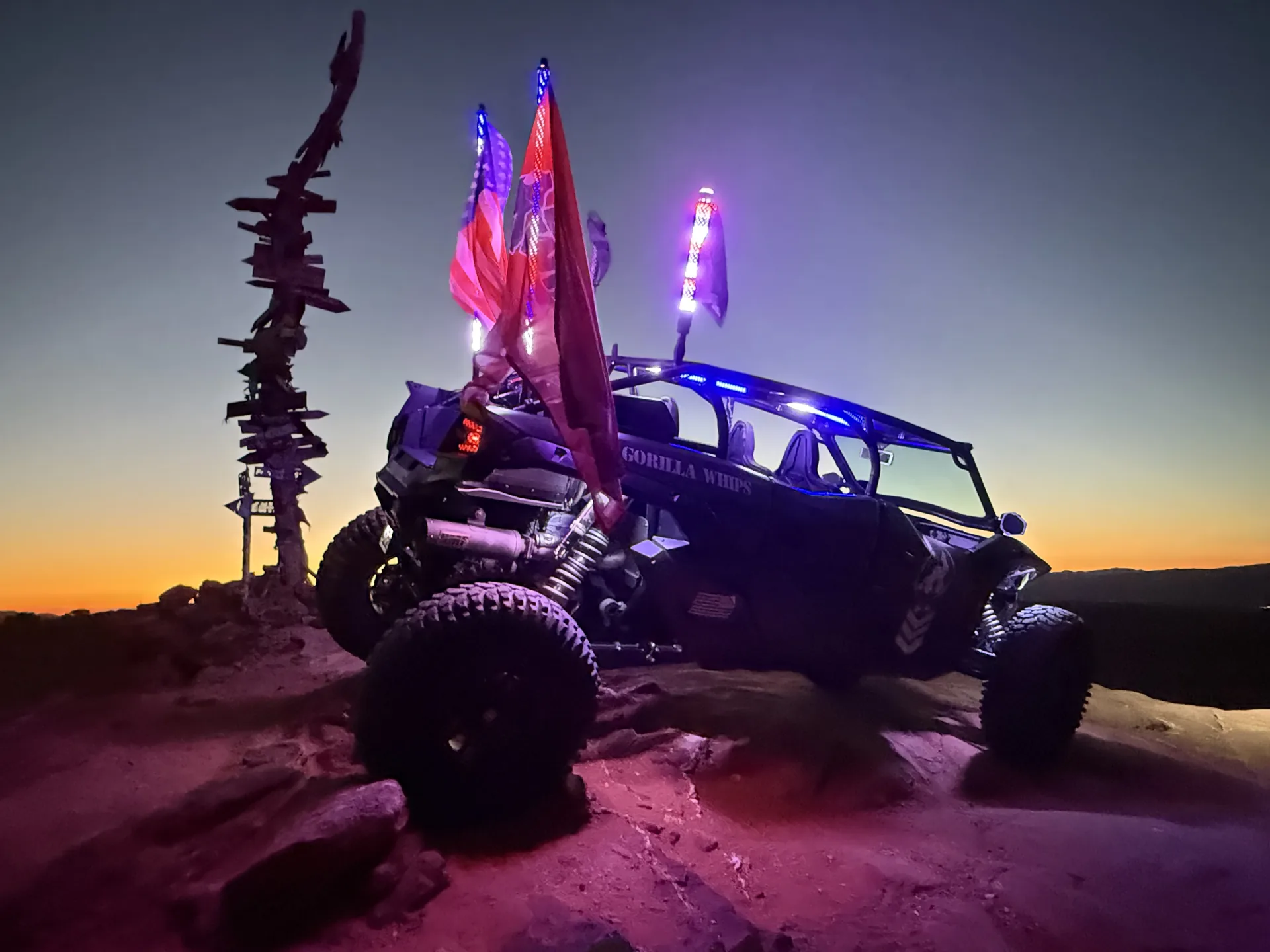 Off-road vehicle and whip flags at desert sunset