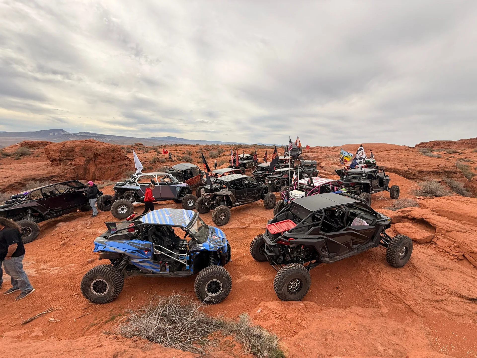 Off-road vehicles and flags gathered on a red-rock trail
